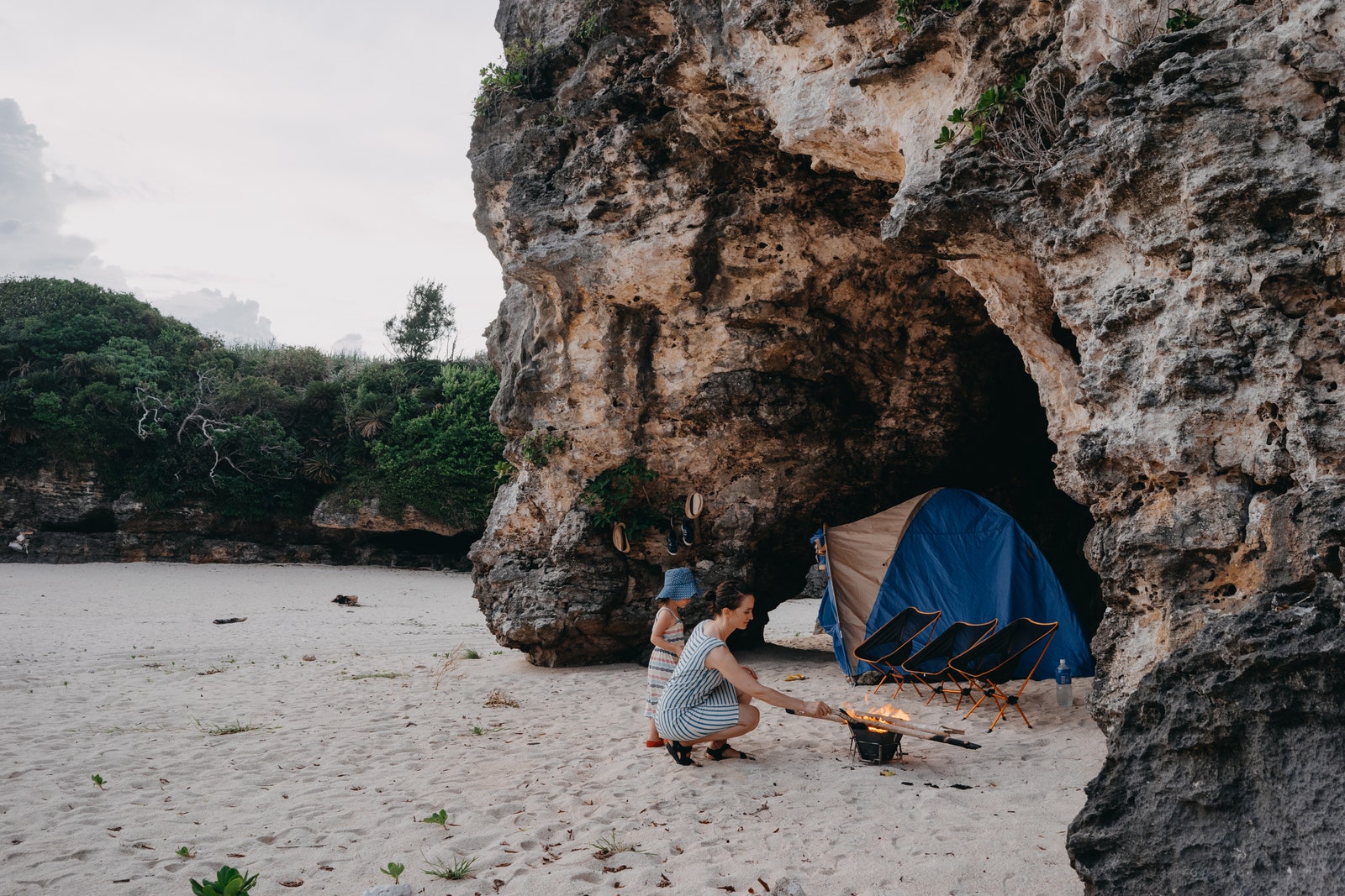 Mother and child enjoying camping in cave on beach with campfire and tent Okinoerabu Island of the Amami Islands...