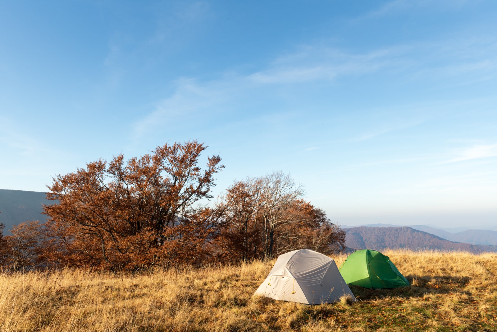Two tents on amazing meadow in autumn mountains