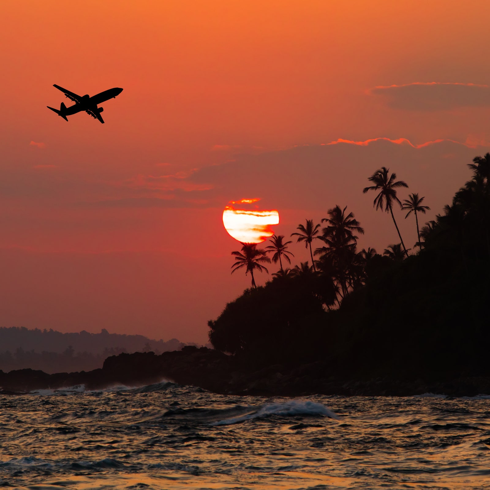 Tropical beach at sunset and a flying plane. Travel to a seaside resort