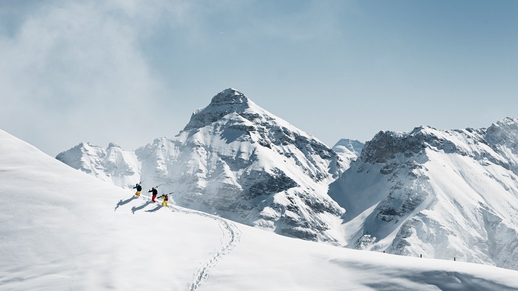 group of skiers hiking up a hill in the backcountry to reach untracked powder slopes in the austrian alps.