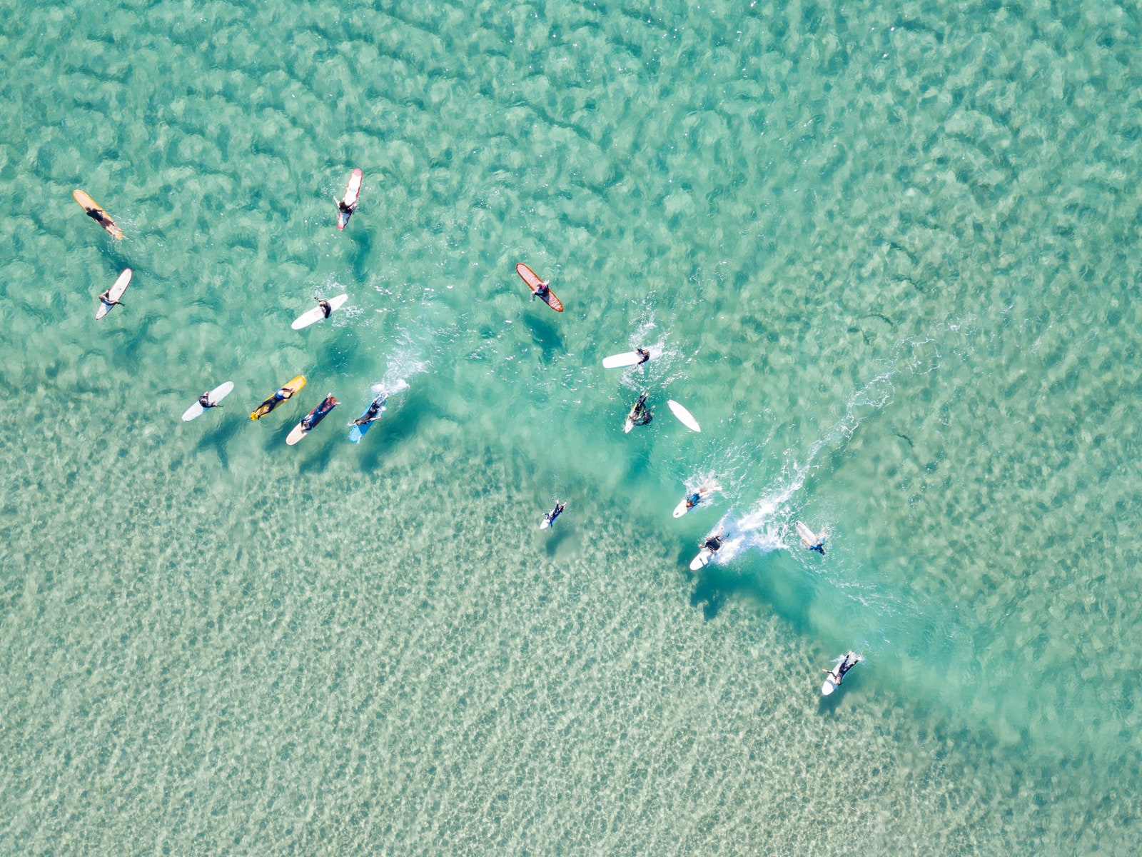 looking down on crystal clear waters with surfers coastline Australia